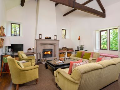 A living room with a fireplace two armchairs sofas a coffee table and windows at Bank Barn Wreay Watermillock