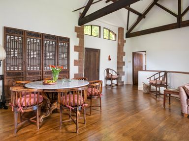 A dining area with a round marble table and six wooden chairs with red cushions at Bank Barn Wreay in Watermillock