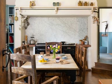 A dining area with a wooden table and chairs a vase of flowers and breakfast items at Bank Barn Wreay Watermillock