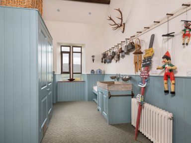 A utility room with blue cabinets a concrete sink wall-mounted bells and puppets at Bank Barn Wreay Watermillock