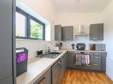 A kitchen with grey cabinets a sink oven microwave and a window at 6 Strathtay Lodges in Aberfeldy