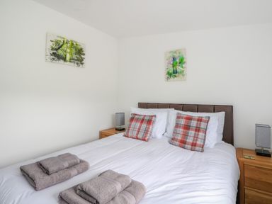 A bedroom with a double bed two bedside tables two lamps and folded towels at 6 Strathtay Lodges in Aberfeldy