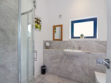 A bathroom with a glass shower enclosure wall sink window and mirror at 6 Strathtay Lodges in Aberfeldy