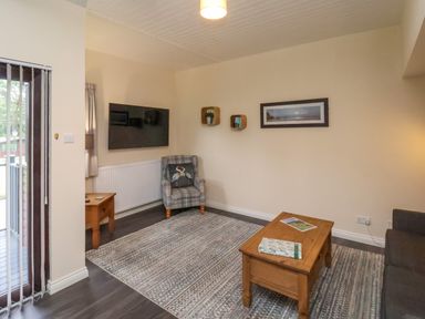 A living room with a patterned armchair coffee table and wall mounted TV at Cowslip in Saltburn-By-The-Sea