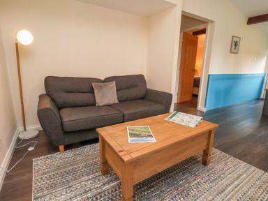 A living room with a gray sofa a wooden coffee table on a rug and a floor lamp at Cowslip in Saltburn-By-The-Sea