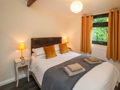 A bedroom with a double bed bedside tables lamps and window with curtains at Cowslip in Saltburn-By-The-Sea