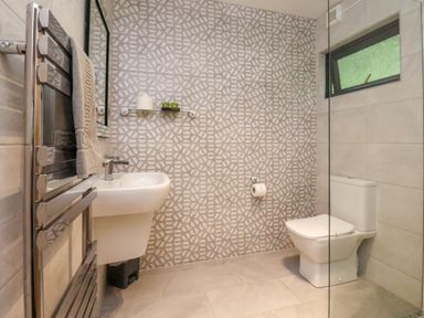 A bathroom with a sink a toilet a towel rack and a patterned wall at Cowslip in Saltburn-By-The-Sea
