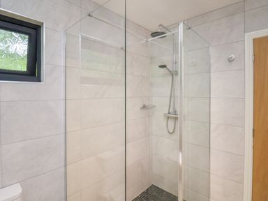 A bathroom with a glass enclosed walk in shower a showerhead and a wooden door at Cowslip in Saltburn-By-The-Sea