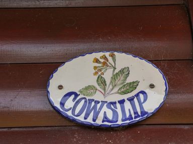 An oval ceramic sign with a flower design and the word Cowslip on a wooden surface at Cowslip in Saltburn-By-The-Sea
