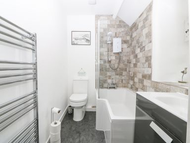 A bathroom with a bathtub shower combination toilet sink and towel rack at Penrallt in Rhydlydan
