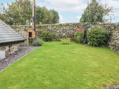 A garden with grass and stone walls and plants at Penrallt in Rhydlydan