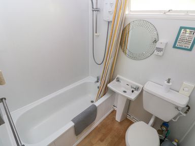 A bathroom with a bathtub shower toilet sink mirror and soap dispenser at Milkwood in Elmrise Park near Llansteffan
