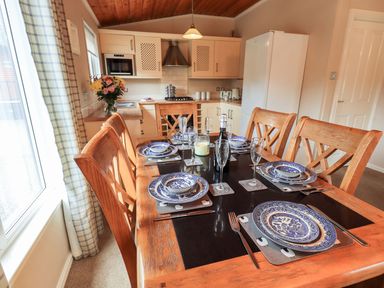 A dining table set with blue and white plates and glasses in a kitchen at Brightwater Lodge White Cross Bay near Windermere