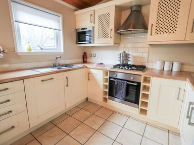 A kitchen with a window sink stove oven microwave and cabinets at Brightwater Lodge White Cross Bay near Windermere