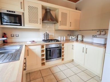 A kitchen with cream cabinets stove oven microwave and sink at Brightwater Lodge White Cross Bay near Windermere