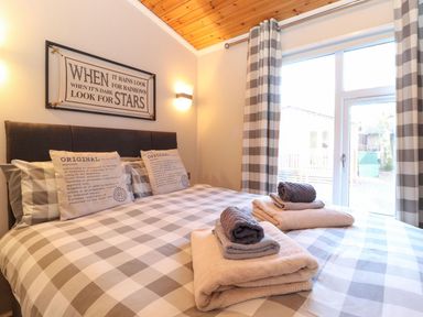 A bedroom with a bed with checkered bedding and towels on the bed at Brightwater Lodge White Cross Bay near Windermere