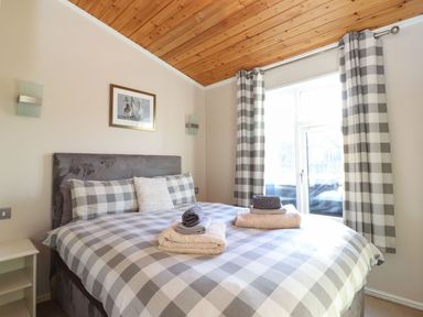 A bedroom with a checkered bedspread and matching curtains at Brightwater Lodge White Cross Bay near Windermere