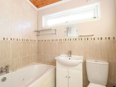 A bathroom with a bathtub sink with cabinet and toilet at Brightwater Lodge White Cross Bay near Windermere