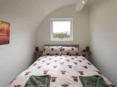 A bedroom with a bed featuring animal print bedding green towels on the bed and a window above the headboard at Shepherds View in Castlerigg near Keswick