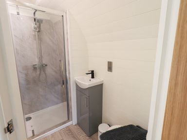 A bathroom with a shower enclosure a sink with cabinet and a toilet with a rug at Shepherds View Castlerigg near Keswick