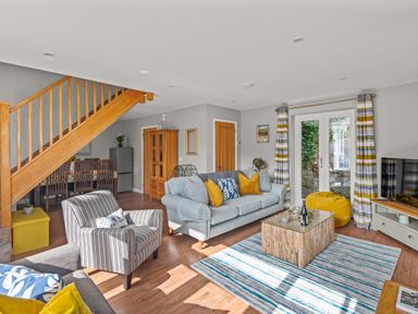 A living room with sofas a striped armchair a coffee table and a dining area near stairs at Seascape Kingsand