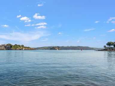 A wide view of a body of water with land on both sides and a partly cloudy sky at Seascape in Kingsand