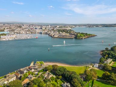 A coastal town with buildings green areas and boats on the water at Seascape in Kingsand