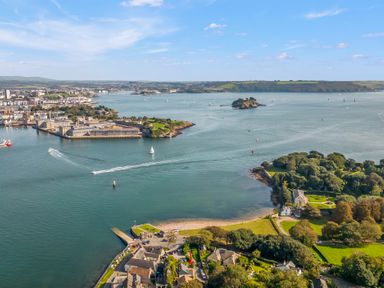 An aerial view of a harbor with boats sailing near a coastline with buildings and green areas at Seascape in Kingsand