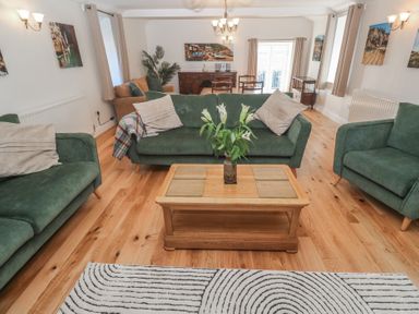 A living room with green sofas wooden coffee table and dining area at Tremornah Lamorna