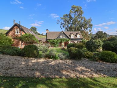 A house with a gravel pathway and bushes in the garden at Highgrove Barn in Painswick
