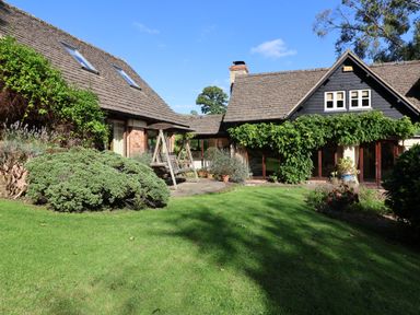 A house with a garden and bushes and a wooden swing at Highgrove Barn in Painswick