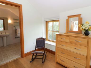 A bedroom with a rocking chair and dresser at Bryn Isaf in Swyddffynnon near Pontrhydfendigaid
