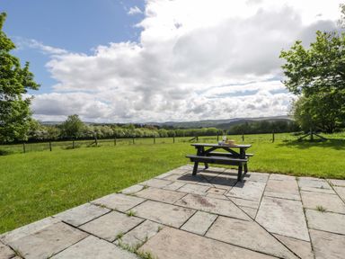 A picnic table on a slate patio with grass in Bryn Isaf near Swyddffynnon near Pontrhydfendigaid