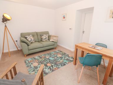 A living room with a sofa, table, and lamp at Mys Hedra Farm in St Buryan