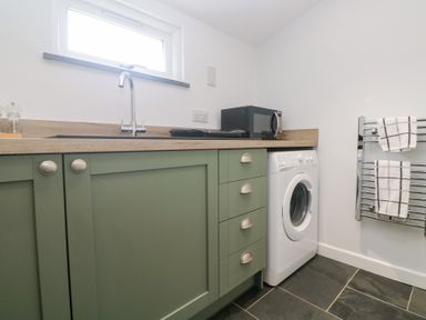 A utility room with a washing machine and microwave at Mys Hedra Farm St Buryan