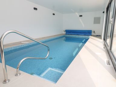 An indoor pool with a handrail and pool cover at Mys Hedra Farm in St Buryan