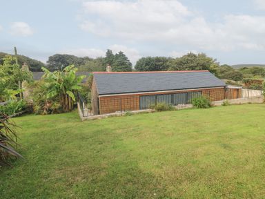An outdoor view of a building surrounded by grass and plants at Mys Hedra Farm in St Buryan