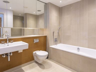 A bathroom with a wall-mounted sink a toilet and a bathtub with a handheld shower at 21 Dart Marina in Dartmouth
