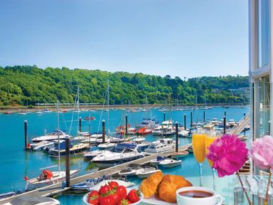 A marina with boats docked on the water with breakfast items on a table and flowers in Dartmouth