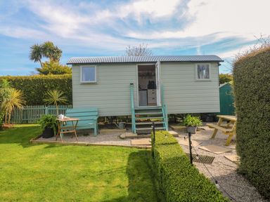 A shepherd hut with steps and furniture in a garden at Higher Merther Farm Shepherds Hut Helston
