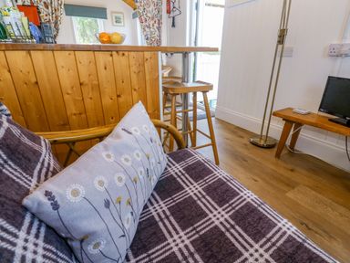 A living room with a sofa and bar stools at Higher Merther Farm Shepherds Hut in Helston