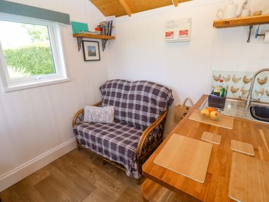 A kitchen with a sofa and table at Higher Merther Farm Shepherds Hut in Helston