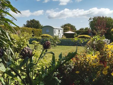 A garden with flowers and a caravan at Higher Merther Farm Shepherds Hut Sithney near Helston