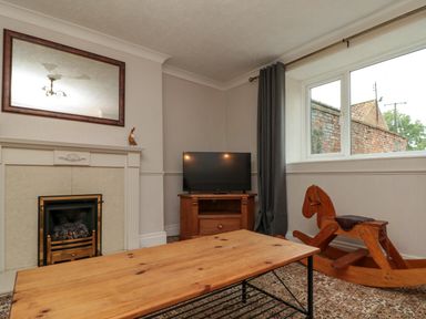A living room with a fireplace TV on wooden stand wooden rocking horse and wooden coffee table at Bellmanear Farm Cottage North Grimston near Malton