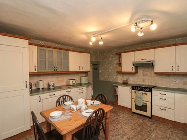 A kitchen with a wooden dining table set for four and white cabinets at Bellmanear Farm Cottage North Grimston near Malton