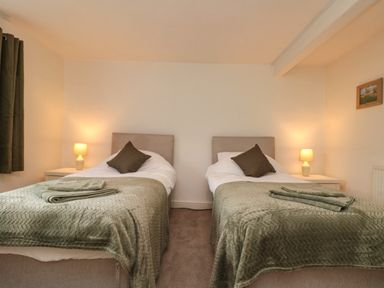 A bedroom with two single beds with green blankets and pillows at Bellmanear Farm Cottage in North Grimston near Malton