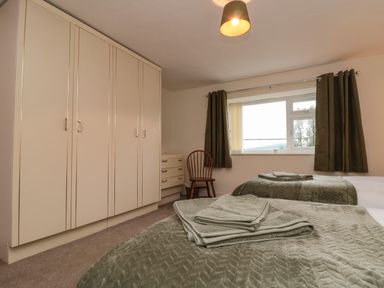 A bedroom with two single beds green bedspreads towels on beds a wooden chair and built in wardrobes at Bellmanear Farm Cottage in North Grimston near Malton