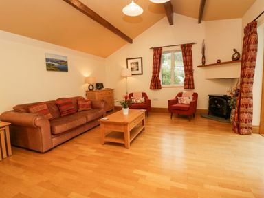 A living room with a brown sofa and red armchairs around a wooden coffee table at Blue Hill House in Ambleside