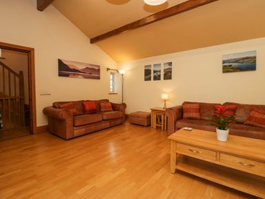A living room with two brown sofas a wooden coffee table with a plant and landscape pictures on walls at Blue Hill House in Ambleside