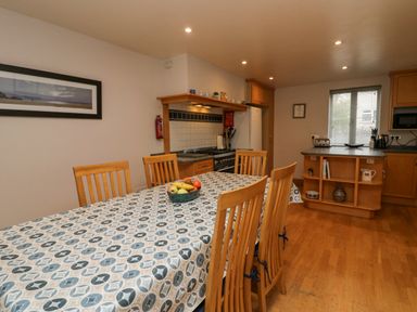 A kitchen with a dining table covered with a patterned tablecloth and wooden chairs at Blue Hill House in Ambleside
